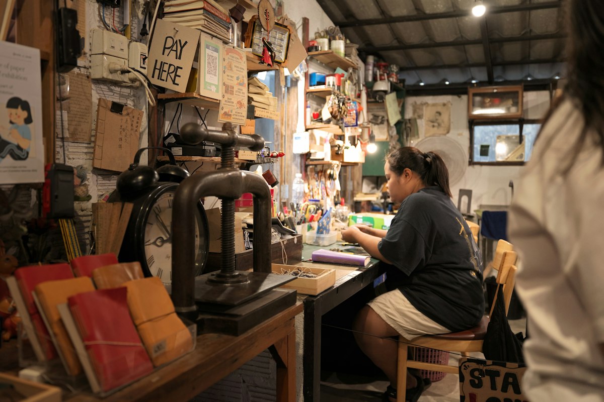 Des mains au travail sur un établi d'atelier, entourées de papier.