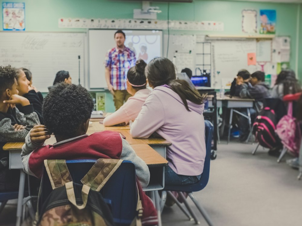 Une classe suit une présentation, assise en groupe.