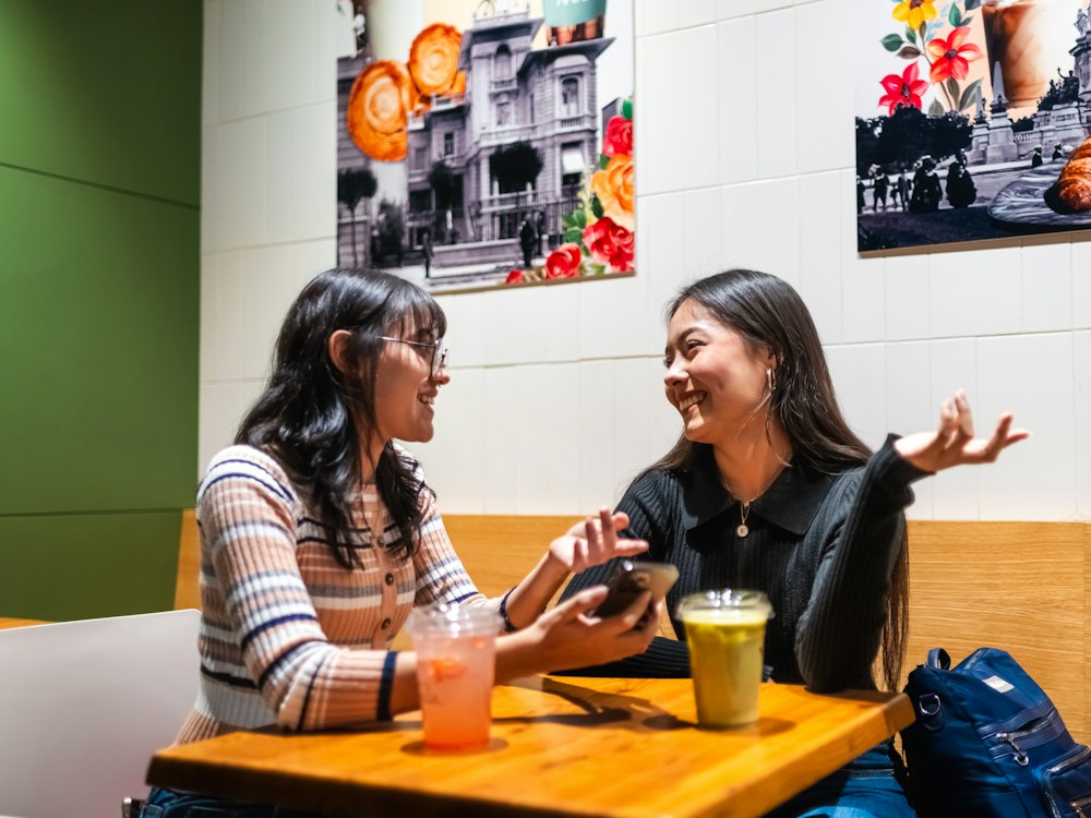 Deux jeunes femmes discutent à la table d'un café.